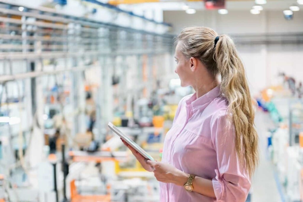 女性工程師在工廠產線環境中手持資料，正在評估與進行包裝機械選購決策。